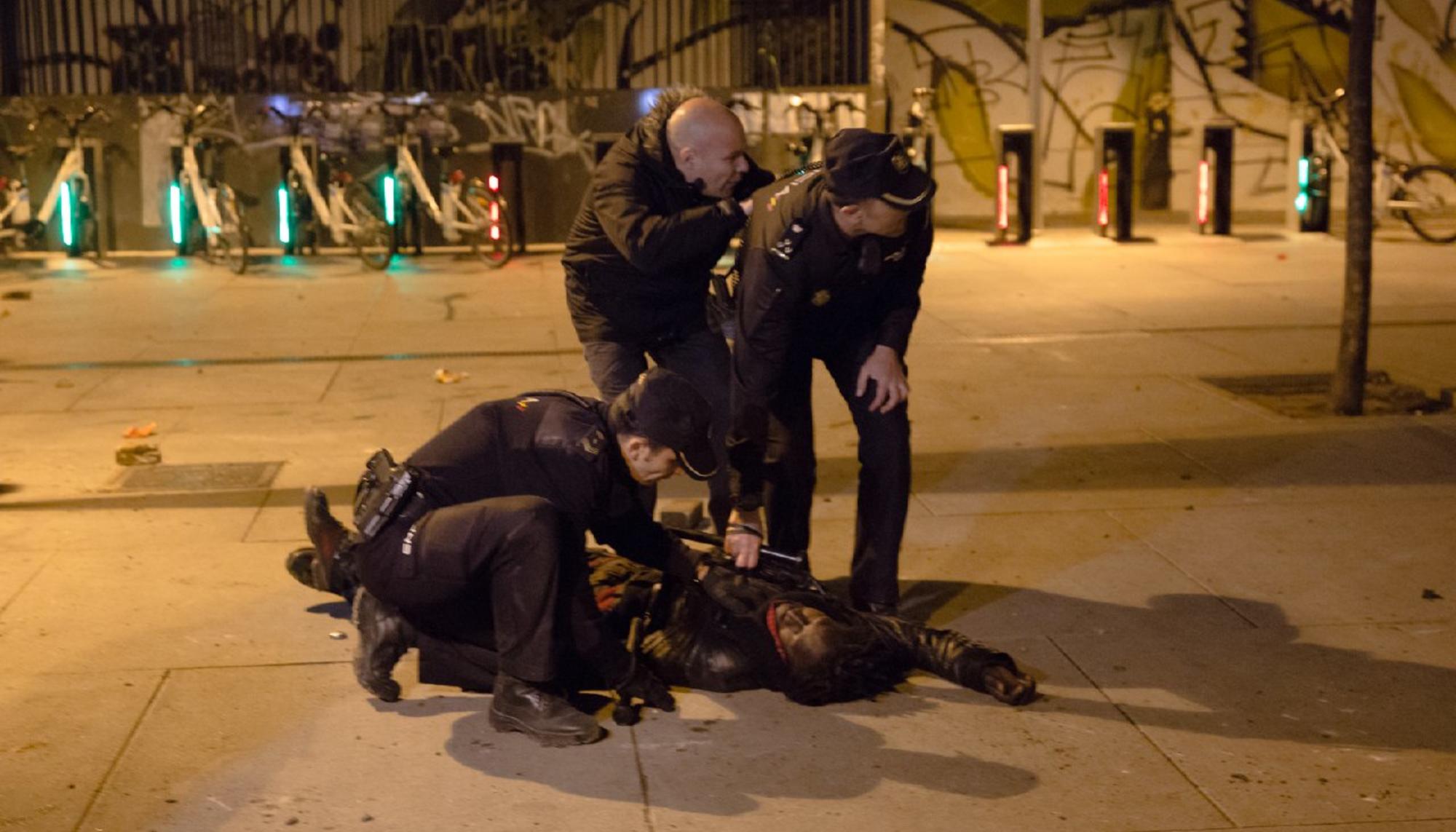 Agentes de policía reducen a un hombre durante los disturbios en Lavapiés tras la muerte de Mame Mbaye